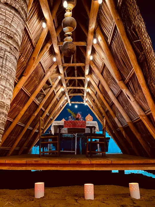 Mesa con velas bajo la palapa de noche