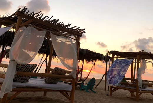 Camas con dosel en la playa al atardecer