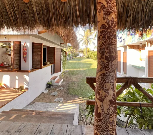 Pasillo techado con poste de madera tallada en el club de playa