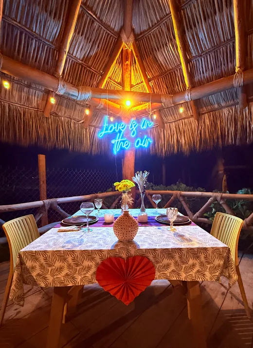 Montaje romantico con letrero de neon bajo la palapa
