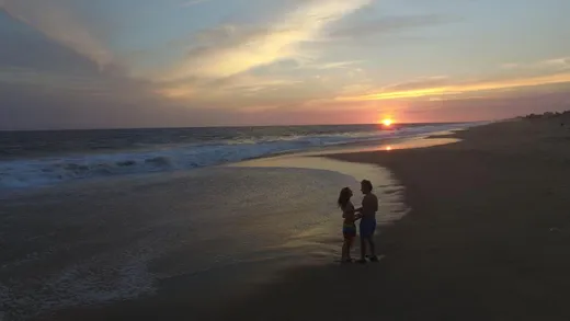 Pareja viendo la puesta del sol en la playa